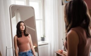 Young teenage girl looking in the mirror in the room.